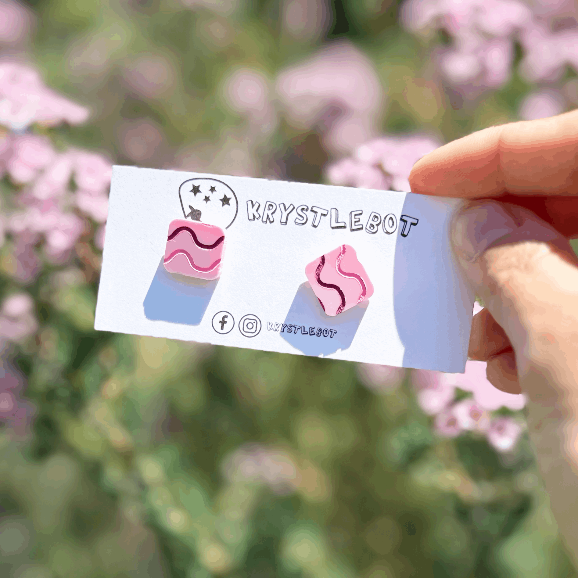 Pink and purple wave painted square shaped earrings on a floral background 