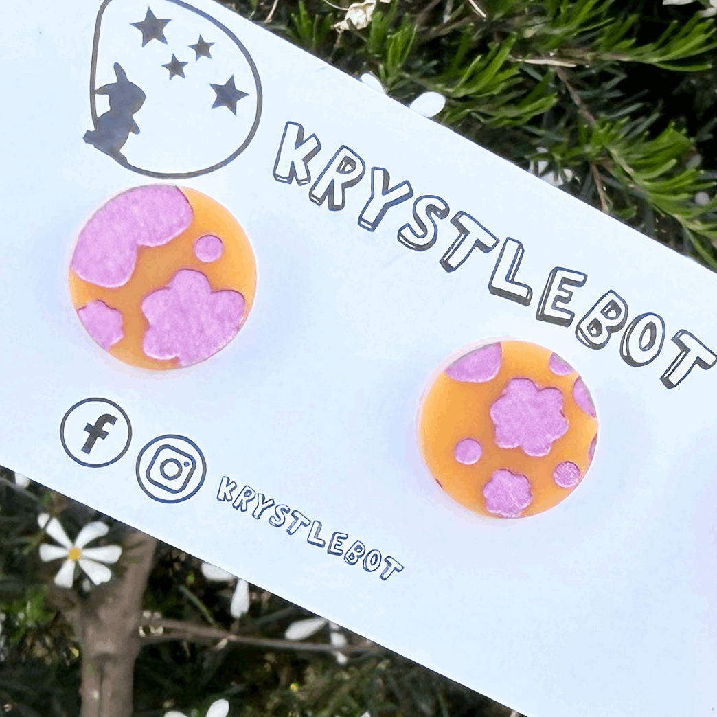 Pair of circle round orange acrylic earrings hand painted with pink metallic abstract flowers