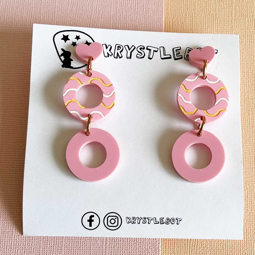 Pair of pink circle acrylic earrings with white and orange painted waves in the centre. Teacher earrings, pink and lightweight 