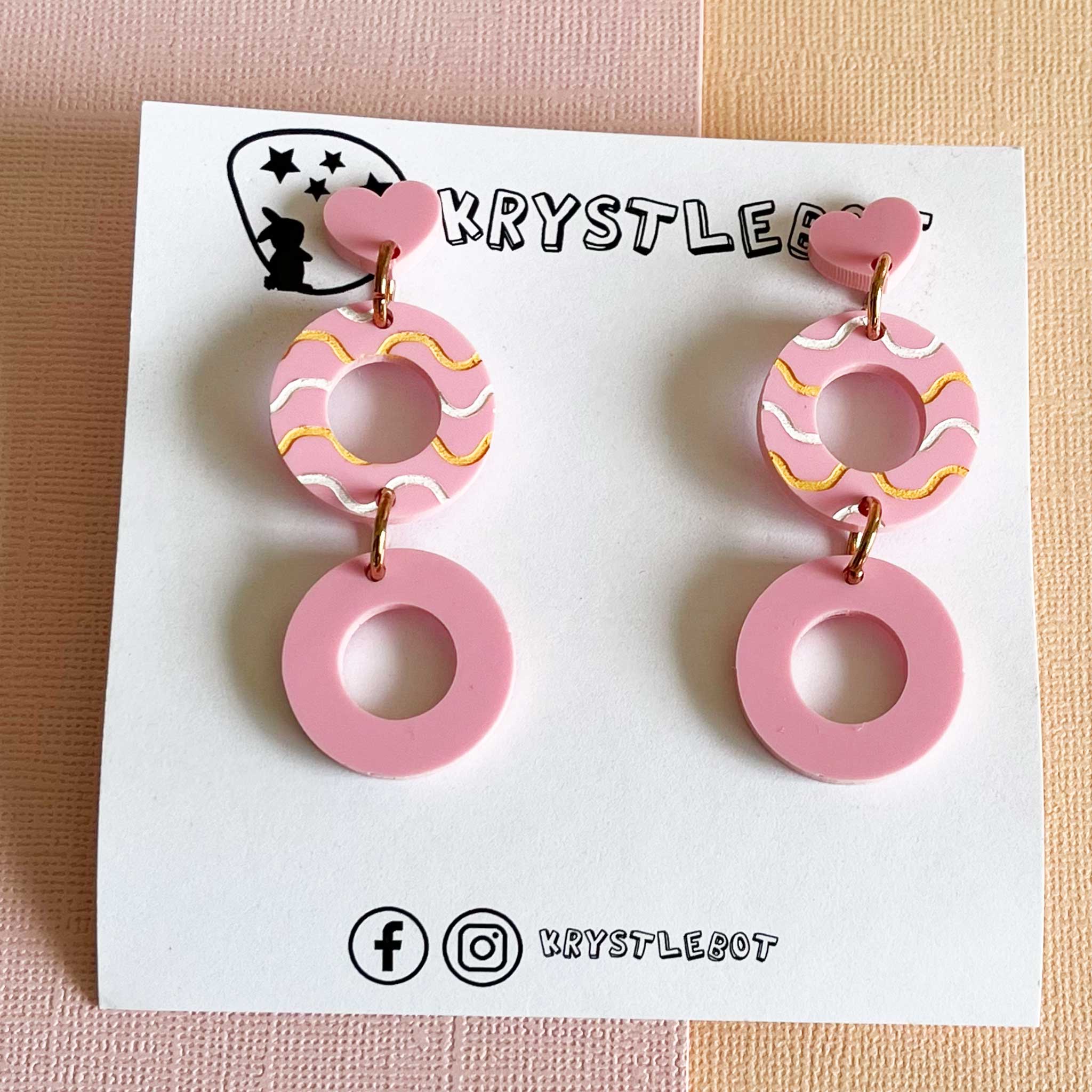 Pair of pink circle acrylic earrings with white and orange painted waves in the centre. Teacher earrings, pink and lightweight 